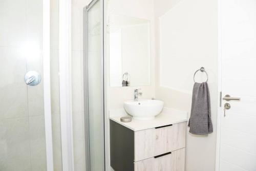 La salle de bains blanche est pourvue d'un lavabo et d'une douche. dans l'établissement The Mansioners Apartment, à Midrand