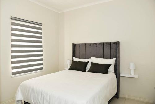 a bedroom with a large white bed with black pillows at The Mansioners Apartment in Midrand