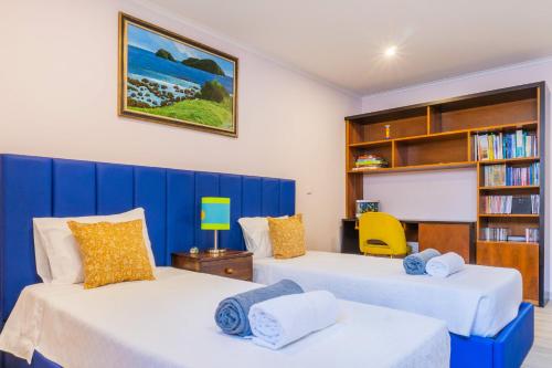 a bedroom with two beds and a book shelf at Pinheiro SUN&BEACH House in Ponta Delgada