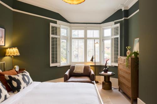 1 dormitorio con 1 cama, 1 silla y ventanas en The Cranley Gardens Escape - Spacious 2BDR Flat, en Palmers Green