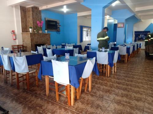 a man standing in a room with tables and chairs at BROKS Hotel e Restaurante in Fraiburgo