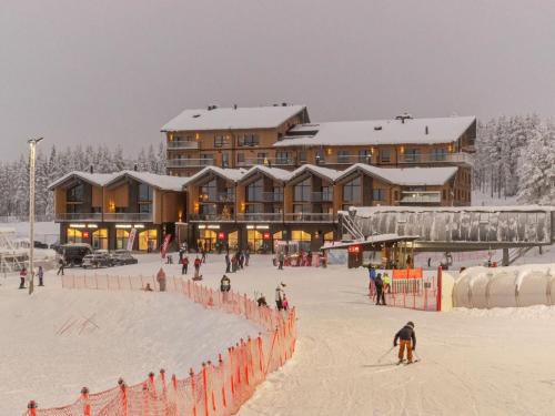 grupa ludzi jeżdżących na nartach w śniegu przed domkiem w obiekcie Holiday Home Villa jääpolte by Interhome w mieście Sirkka