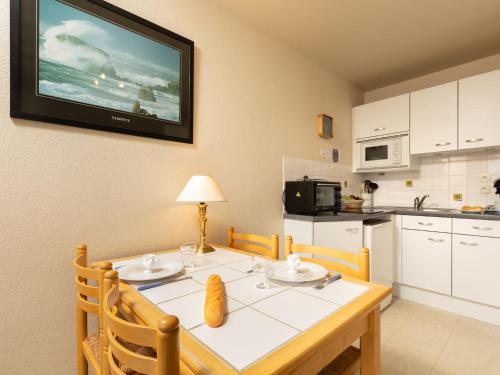 une cuisine avec une table avec des chaises et une télévision au mur dans l'établissement Apartment Les Bisquines de la Houle by Interhome, à Cancale