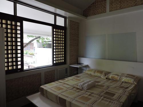 a bedroom with a bed and a large window at Orange Mangrove Pension House by SMS Hospitality in Puerto Princesa City