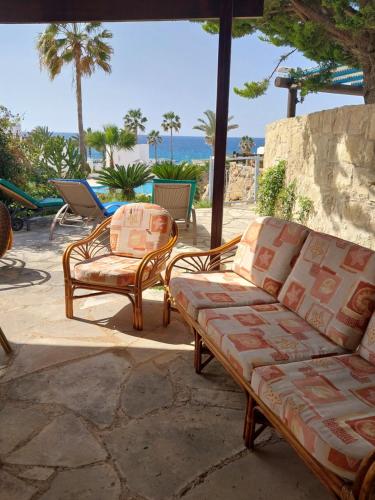 two chairs and a couch on a patio with the ocean at Villa Margo by the Sea in Paphos City