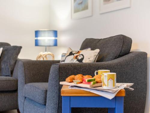 a coffee table with a tray of pastries on a couch at Holiday Home Marshmallow House by Interhome in St Austell