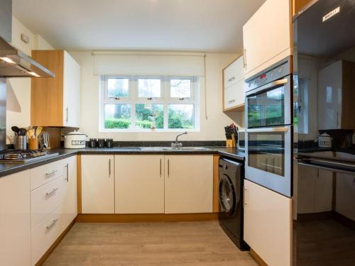 cocina con armarios blancos y lavavajillas en Holiday Home Marshmallow House by Interhome, en St Austell