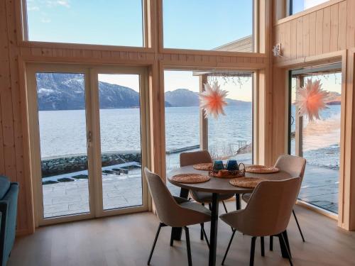 - une salle à manger avec une table, des chaises et des fenêtres dans l'établissement Holiday Home Hildebu - FJS156 by Interhome, à Sørbø