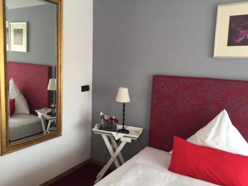 a bedroom with a mirror and a bed and a table at Hotel Heddernheimer Hof in Frankfurt/Main