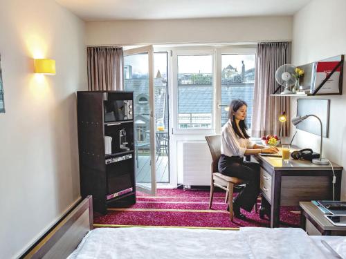 a woman sitting at a desk in a hotel room at Apartment BHMS Lakeside Campus by Interhome in Lucerne