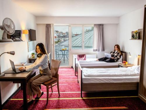 zwei Frauen in einem Hotelzimmer mit Laptops in der Unterkunft Apartment BHMS Lakeside Campus by Interhome in Luzern