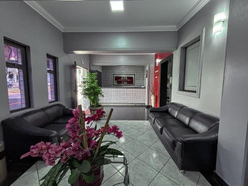 a living room with black leather couches and flowers at Carlton Express Imbiara in Araxá