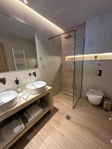 a bathroom with two sinks and a shower at Meteora Gold and Glass in Kalabaka