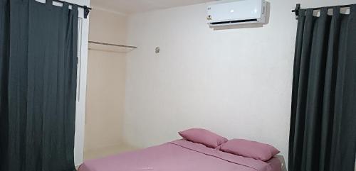 a room with a bed with pink sheets and a window at alojamiento económico in Mérida