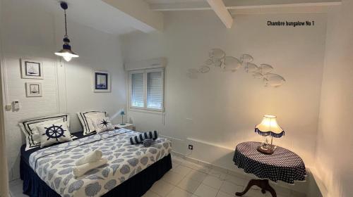 una camera con letto e tavolo con lampada di Les bungalows de la plage a La Trinité