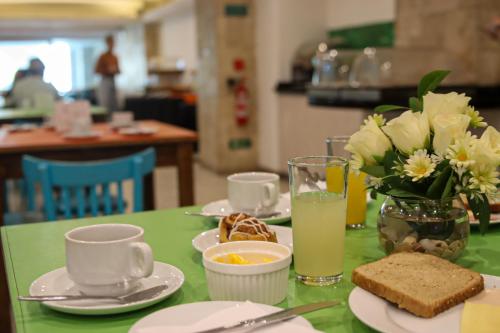 a green table with plates of food and a vase of flowers at Hotel Terrano Concepción in Concepción