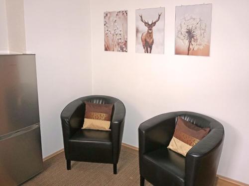 two black chairs in a room with pictures on the wall at Apartment Sandra Falch by Interhome in Flirsch