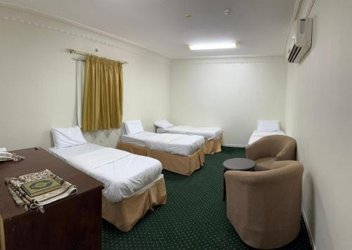 فندق البركة رويال في مكة المكرمة: غرفة بثلاث اسرة ومكتب وكرسي