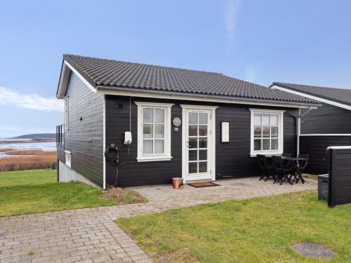 a black house with a patio in front of it at Holiday Home Ewelina - 150m from the sea in Funen by Interhome in Bagenkop