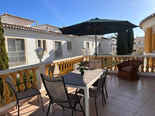 a table and chairs with an umbrella on a balcony at Dream House Near the Beach in Porches