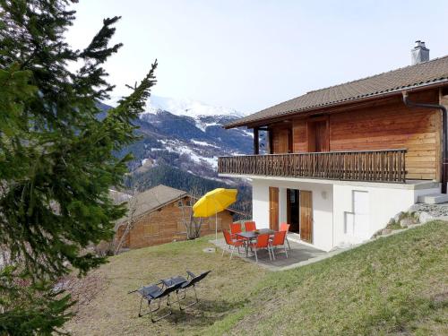 a house with a table and chairs and a yellow umbrella at Apartment Chalet Gredetsch by Interhome in Bürchen