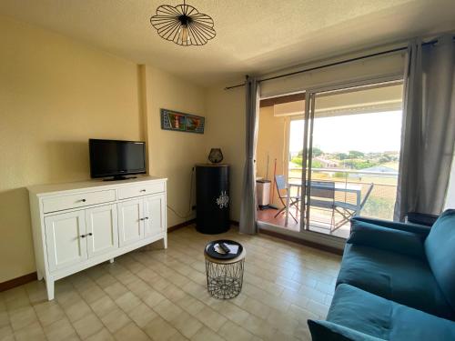 a living room with a couch and a tv and a balcony at Les Sardines in Valras-Plage