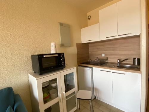 a small kitchen with a microwave and a sink at Les Sardines in Valras-Plage