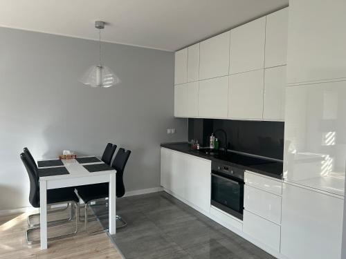 uma cozinha com armários brancos e uma mesa e cadeiras em Apartament Gwiazdowa em Lódź