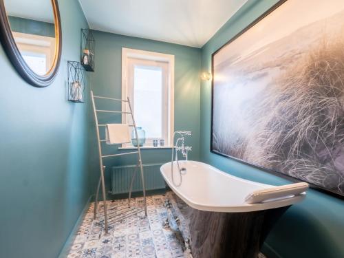 een badkamer met een bad en een groot schilderij aan de muur bij Holiday Home Villa Nora by Interhome in Blankenberge