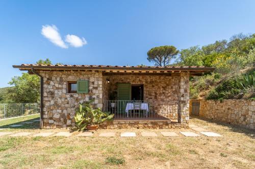 a stone house with a porch with a table and chairs at Apartments La Tenuta where the sea meets the land - Goelba in Porto Azzurro