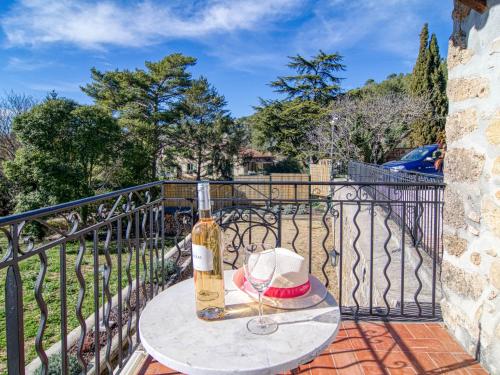 a bottle of wine and a hat on a table on a balcony at Holiday Home La maison aux volets bleus by Interhome in Entrecasteaux