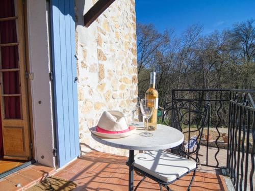 a table with a hat and a bottle of wine on a balcony at Holiday Home La maison aux volets bleus by Interhome in Entrecasteaux