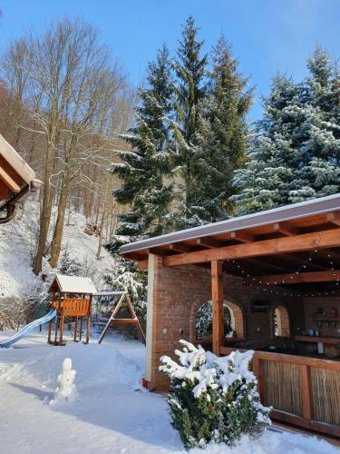 a snow covered porch of a house with a playground at Penzion Ema in Šumperk