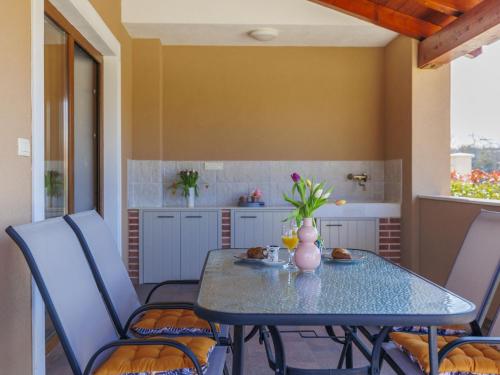 a table and chairs in a room with a kitchen at Apartment Emili by Interhome in Vižinada