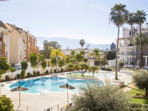 Blick auf einen Pool mit Palmen und Gebäuden in der Unterkunft Apartment Victoria Playa III PLus by Interhome in Denia
