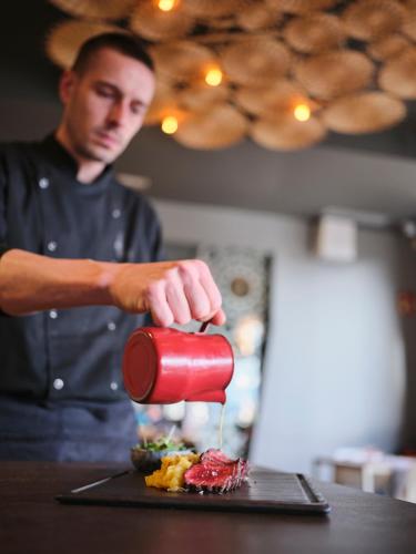 a man is preparing a meal with a redvelt at Qgat Restaurant Events & Hotel in Sant Cugat del Vallès