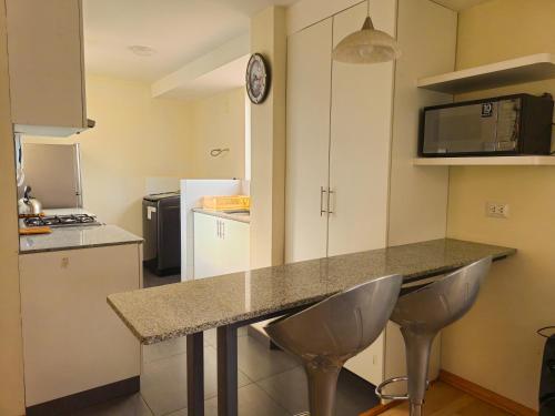 a kitchen with a counter and two stools in it at Fiflos Apartament in Cusco