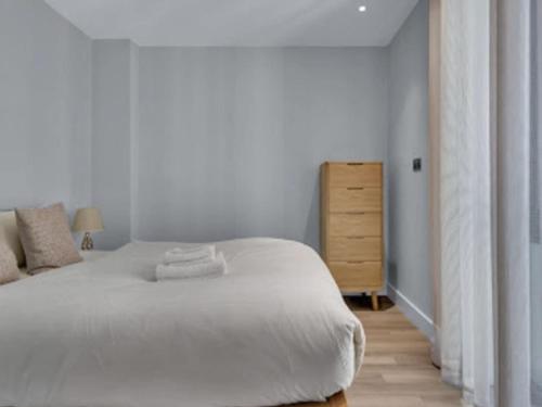 a bedroom with a white bed and a wooden dresser at Apartment Wembley Park apartments-2 by Interhome in London