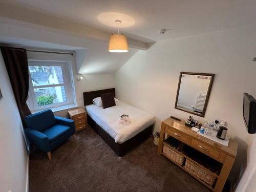 ケズウィックにあるDolly Waggon Guest Houseのベッドルーム1室(ベッド1台、青い椅子、鏡付)