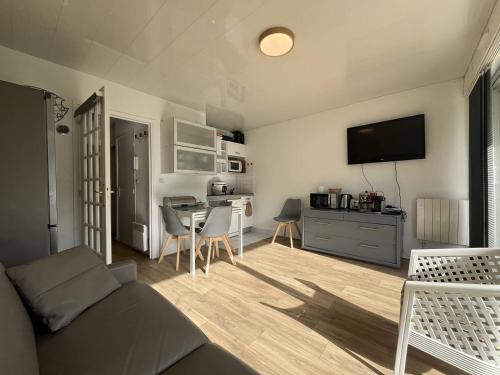 un salon avec un canapé et une table avec une télévision dans l'établissement TourvilleA01, à Le Touquet-Paris-Plage