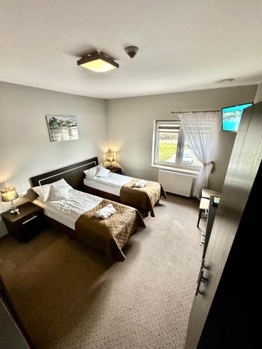 a bedroom with two beds and a television in it at Hotel Pod Dębami in Ostrów Wielkopolski