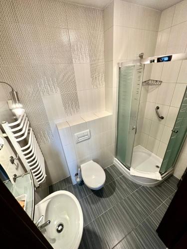 a bathroom with a shower and a toilet and a sink at Hotel Pod Dębami in Ostrów Wielkopolski
