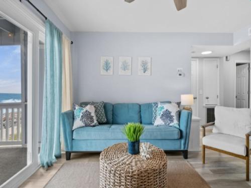 ein Wohnzimmer mit einem blauen Sofa und einem Tisch in der Unterkunft The Sea Willow - Beautiful ocean views! 2nd Floor - Oceanfront! condo in Carolina Beach