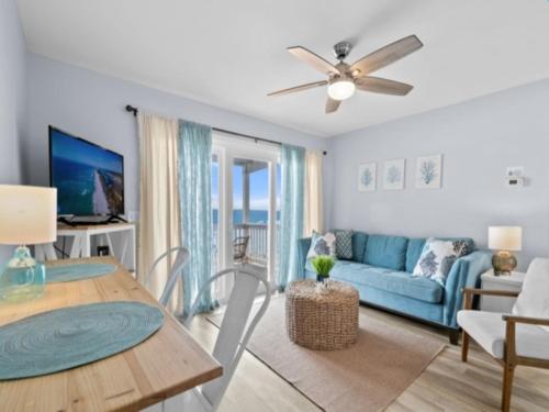 ein Wohnzimmer mit einem blauen Sofa und einem Tisch in der Unterkunft The Sea Willow - Beautiful ocean views! 2nd Floor - Oceanfront! condo in Carolina Beach