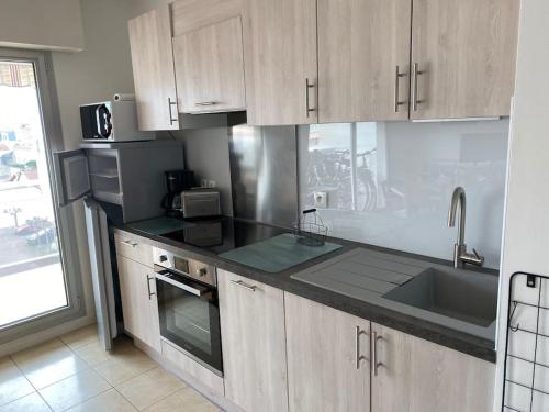 La cuisine est équipée de placards en bois, d'un évier et d'un four micro-ondes. dans l'établissement Appartement en plein centre d'Arcachon, à Arcachon