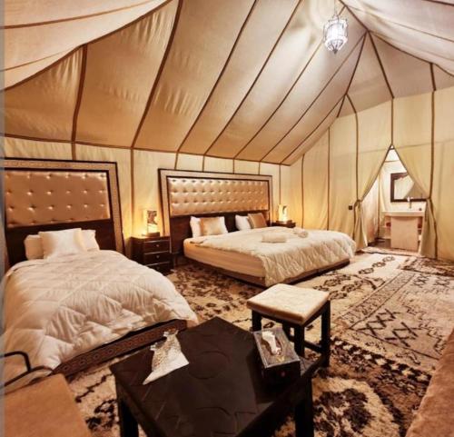 a bedroom with two beds and a table in a room at Galaxy stars camp in Hassilabied