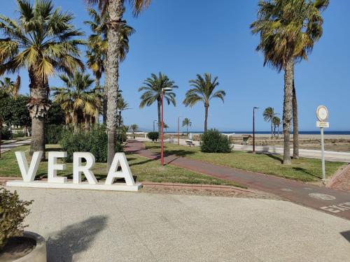 un panneau dans un parc avec des palmiers et l'océan dans l'établissement Casa del Sol - Vera Playa Laguna Beach, à Vera