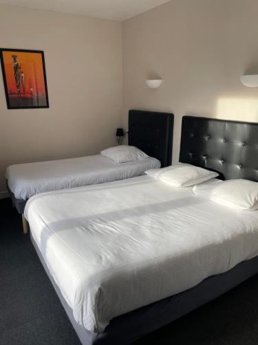 two beds in a hotel room with white sheets at Hôtel La Redoute in Les Rousses