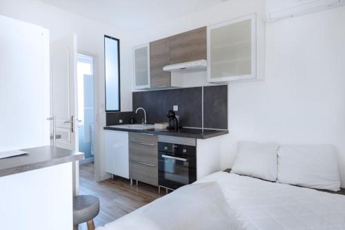 - une cuisine blanche avec un lit et un évier dans l'établissement Appartement cosy au centre de Villeurbanne, à Villeurbanne