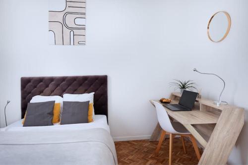 une chambre avec un lit et un bureau avec un ordinateur portable dans l'établissement Appartement cosy au centre de Villeurbanne, à Villeurbanne